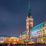 Illuminated Hamburg Town Hall and Christmas Market at night.