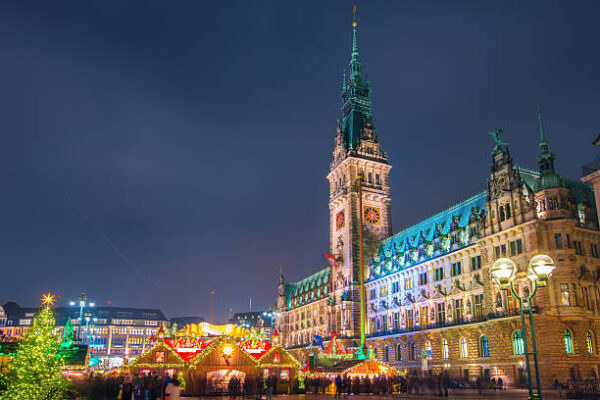 Illuminated Hamburg Town Hall and Christmas Market at night.